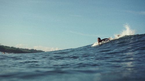 Man swimming in sea against sky