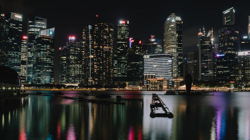 Illuminated buildings by river at night