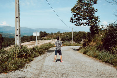 Rear view of woman walking on road amidst trees