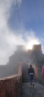 Rear view of people walking on mountain against sky