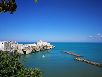 High angle view of town by sea against blue sky