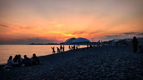 People on beach against sky during sunset