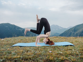 Woman with arms raised on mountain against sky