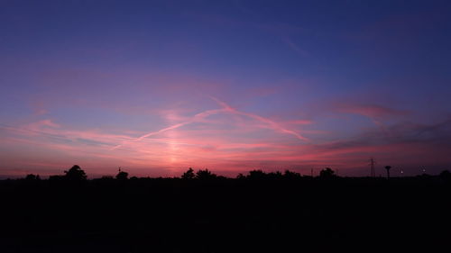 Silhouette trees against dramatic sky during sunset