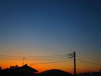 Silhouette electricity pylon against clear sky during sunset