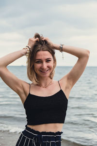 Portrait of young woman standing against sea