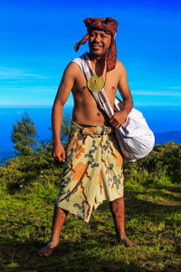 Man in traditional clothes standing on mountain against sky