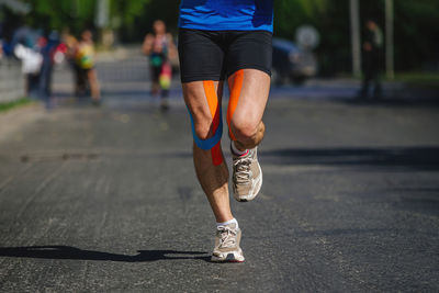 Legs runner man with kinesio taping run marathon	
