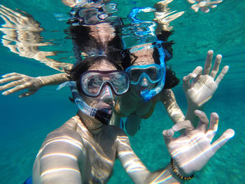 Portrait of young couple showing ok sign while snorkeling in sea