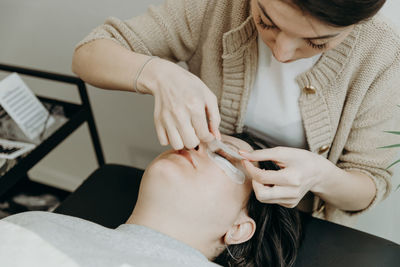 Portrait of a girl cosmetologist extending eyelashes to a woman.