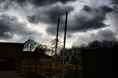 Low angle view of factory against cloudy sky