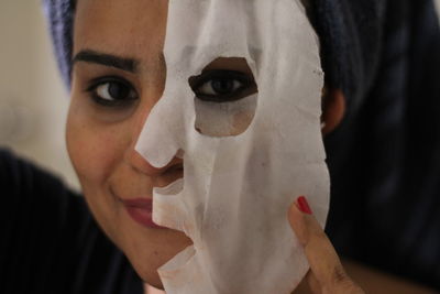 Close-up portrait of smiling woman removing facial mask