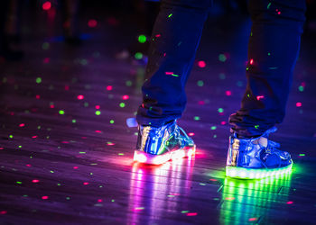 Low section of man wearing illuminated shoes on dance floor