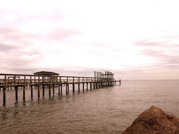 Pier on sea against sky during sunset