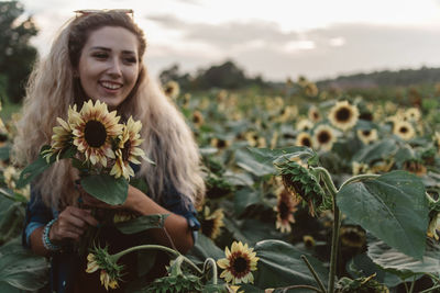 Smiling young woman amidst sunflowers