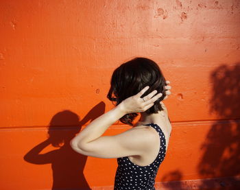 Young woman standing against wall