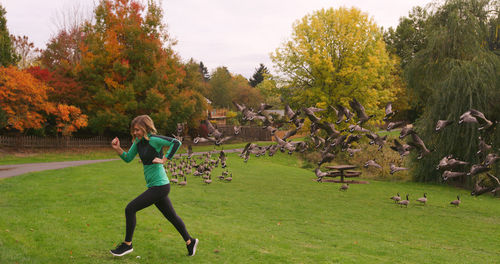 Full length of young woman jogging in park during autumn