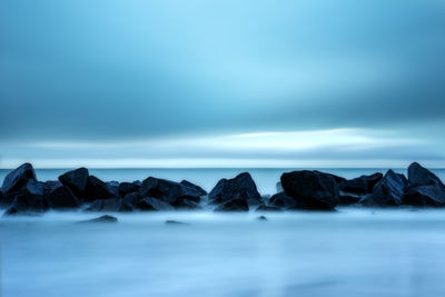 Scenic view of rocks in sea against sky