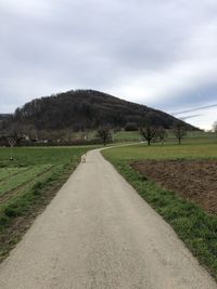 Road amidst field against sky