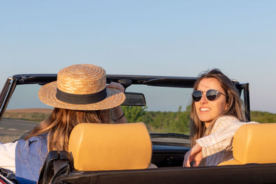 Portrait of smiling young woman wearing sunglasses while sitting in car