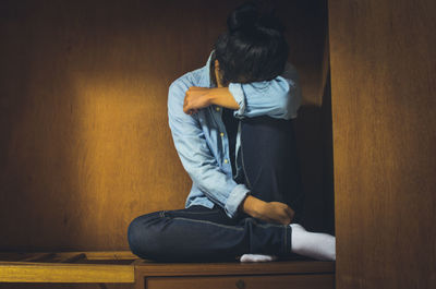 Rear view of woman sitting against wall