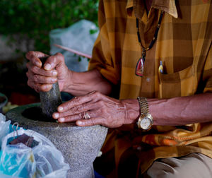 Close-up of man using mortal and pestle