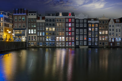 Buildings by river against sky at night