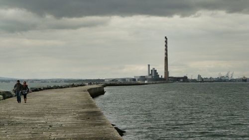 Pier on sea against cloudy sky