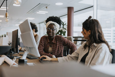 Young female colleagues planning strategy while discussing at desk in office