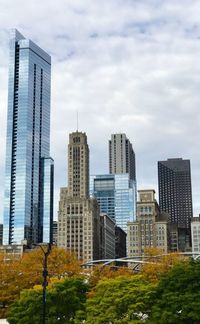 Low angle view of skyscrapers against cloudy sky