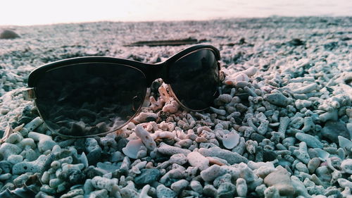 Close-up of sunglasses on pebbles at beach