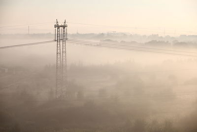 Electric pylon in foggy landscape
