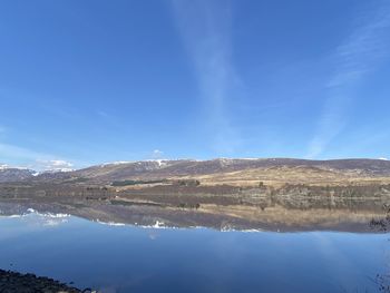 Scenic view of lake and mountains against blue sky