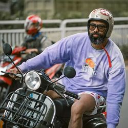 Rear view of man riding motor scooter on street