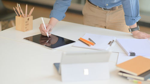Midsection of woman holding paper at table