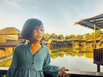 Woman standing by lake against sky