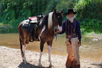 Full length of man standing with horse by river