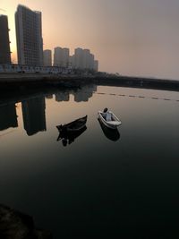 Boats moored in sea against clear sky during sunset