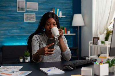 Young woman using mobile phone while sitting on table