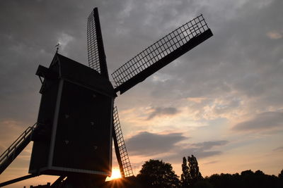 Low angle view of traditional windmill against sky at sunset