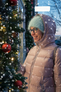 Portrait of woman standing against christmas tree
