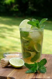 Non-alcoholic mojito summer drink nojito mocktail with wooden muddle, mint leaves on wooden board. 