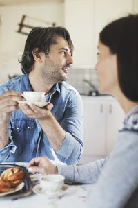 Mid adult man having coffee with woman at breakfast table