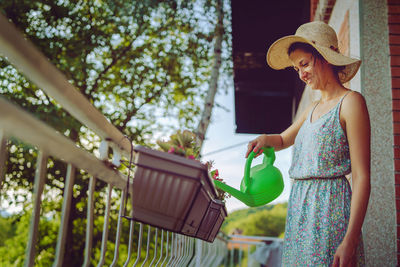 Young beautiful woman watering plants