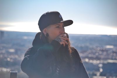 Portrait of young woman in park against sky during winter