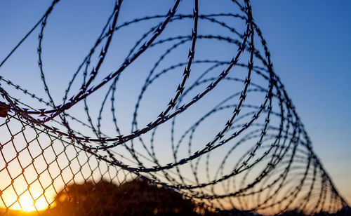 Close-up of barbed wire against sky during sunset