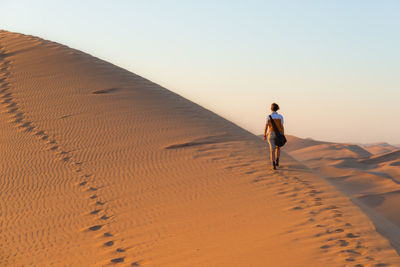 Rear view of man walking on sand at beach