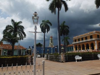 Palm trees and buildings against cloudy sky