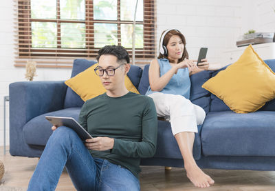 Young woman using mobile phone while sitting on sofa at home