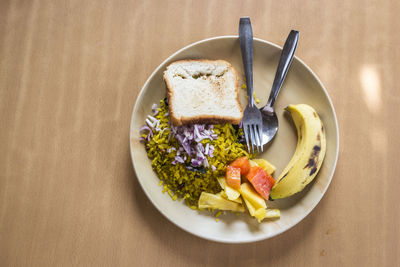 Top view of breakfast dish in india style. it is mix of poha rice, fruit and bread.